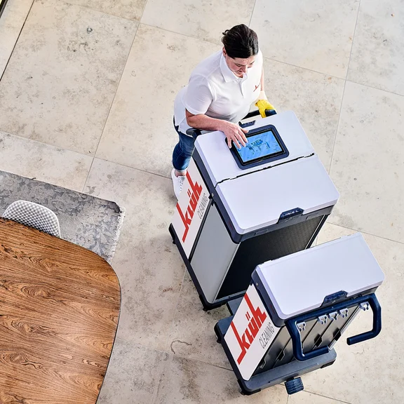 Reinigungskraft mit Tablet und Reinigungswagen 