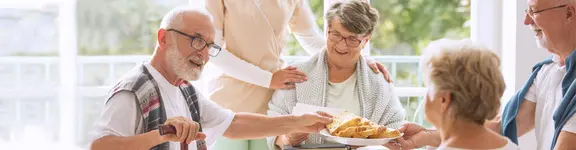 Das Bild zeigt eine Gruppe gut gelaunter Senioren beim Essen, das von Klüh Catering zubereitet wurde.