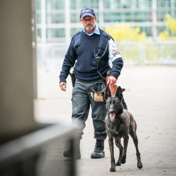 Klüh Wachdienst Angestellter in Arbeitskleidung mit einem Wachhund an der leine
