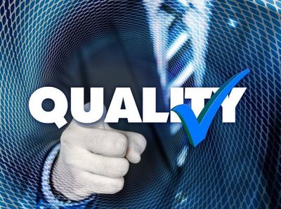 Bild von einem Mann in einem Anzug der mit dem Finger in die Kamera zeigt und mittig im Bild der Schriftzug "Quality" mit einem Hacken darüber 