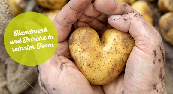 Bannerbild: zwei Hände halten eine herzförmige Kartoffel, im hintergrund sind Kartoffelsäcke und dem Titel: "Handwerk und Frische in reinster Form"
