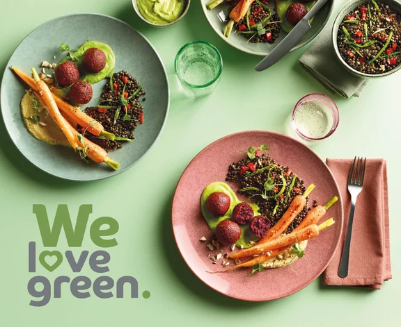 Ein Bild von einem grünen Tisch der gedeckt ist und mit Tellergerichten und dem Slogan "we love green."