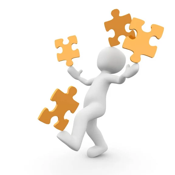 ein weißes Männchen balanciert orangene Puzzelteile auf den Händen, auf dem Fuß und auf dem Kopf