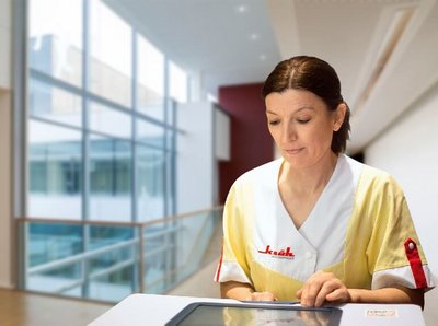 Klüh Reinigungskraft während der Arbeit, bedient ein Tablet