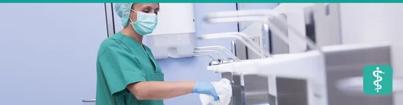 Eine Reinigungskraft säubert im sterilen Raum in Schutzkleidung sorgfältig die Oberflächen.