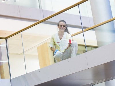 lächelnde Klüh Reinigungskraft wischt eine Glasfassade mit einem weißen Tuch