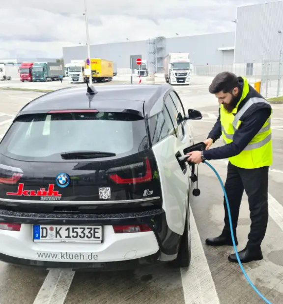 Ein Mitarbeiter von Klüh Security beim Aufladen einen umweltfreundlichen Autos, dass elektrobetrieben ist..