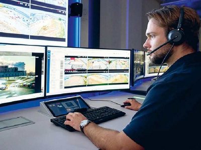 Foto von Mitarbeiter vor mehreren Monitoren mit Kameraansichten.
