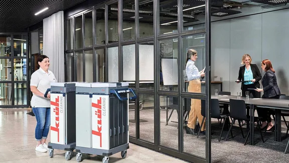 Reinigungsdame läuft in Richtung eines Konferenzraumes, in dem ein smarter Alarm für die benötigte Reinigung ausgelöst wurde