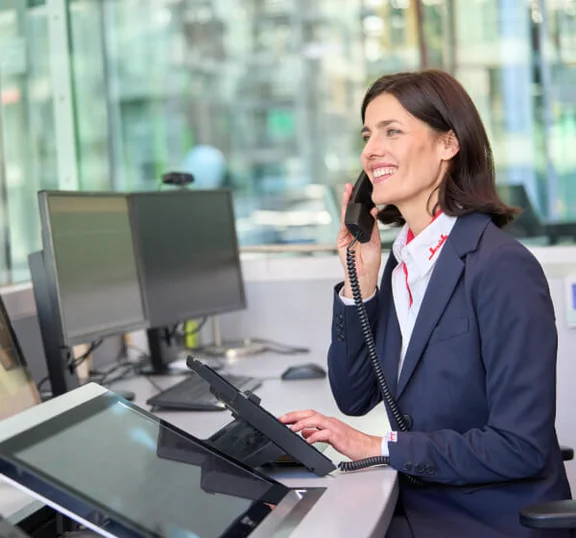 Das Bild zeigt eine weibliche Sicherheitskraft am Empfang, die lächelnd in ein Telefon spricht.