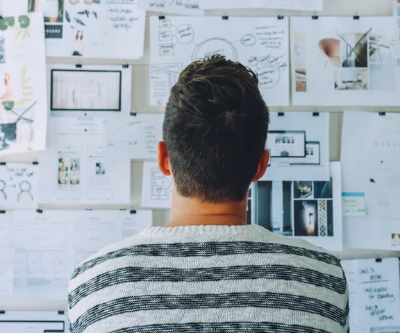 Ein Mann schaut sich eine Wand voller Dokumenten an