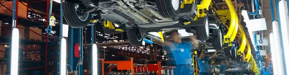 Ein Bild in einer Autofabrik, Männer unter hängenden Autos schrauben