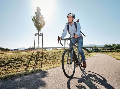 Ein Mann mit Helm sitzt auf einem Fahrrad auf leeren Radweg