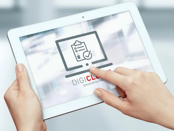 zwei Hände die ein Tablet bedienen und dem Bildschirm ist Digi Clean powered by Klüh zu sehen