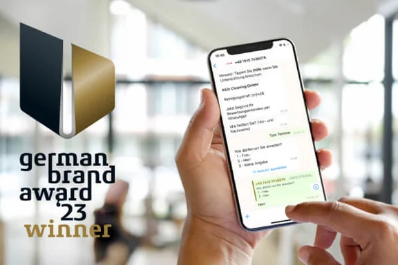 zwei Hände die ein Smartphone bedienen und auf dem Bildschirm ist ein WhatsApp Chat zu sehen, zusätzlich ist auf dem Bild das Logo: german brand award 2023 winner