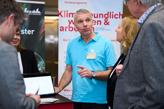 Heribert Rubarth an einem Infostand vom Klimamobil Düsseldorf erklärt etwas den Besuchern