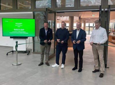 EIn Bild von vier Männern die eine grüne Schleife zur eröffnung des Restaurants zerschneiden im Hintergrund ist das Restaurant Cantinetta