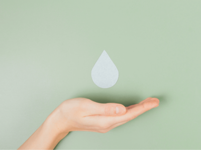 Ein Bild von einer einer nach oben geöffneten Hand an einer grünen Wand mit einem Wassertropfen Sticker, die Hand fängt den Tropfen auf