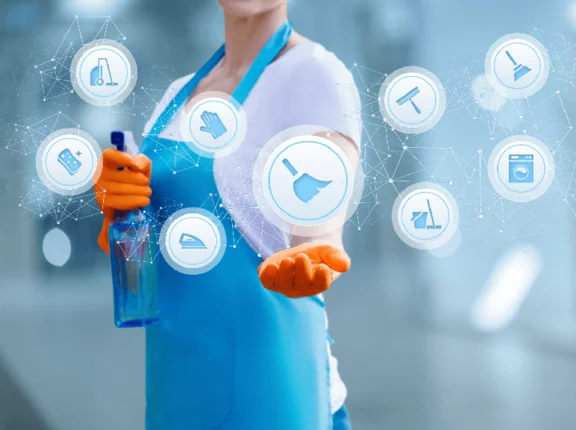 eine Illustration: eine Reinigungskraft in Arbeitskleidung, in einer Hand eine Sprühflasche und die Hand geöffnet die Visuelle Icons hält. Die Visuelle Icons sind: Wischmopp, Bügeleisen, Waschmaschine, Schwamm, Gummihandschuh, Eimer mit Wischmop