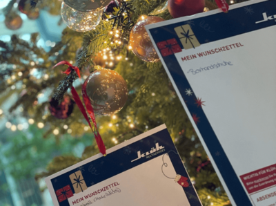 Ein Bild von einem geschmückten Weihnachtsbaum, an dem Baum hängen Zettel mit Klüh Multiservices Logo und dem Titel "Mein Wunschzettel"