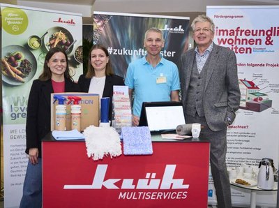 Ein Gruppenbild von 4 Personen an einem Klüh Multiservices Infostand mit dem Klimapakt Düsseldorf, auf dem Tresen sind Waschmittel sowie verschiedene Wischtücher