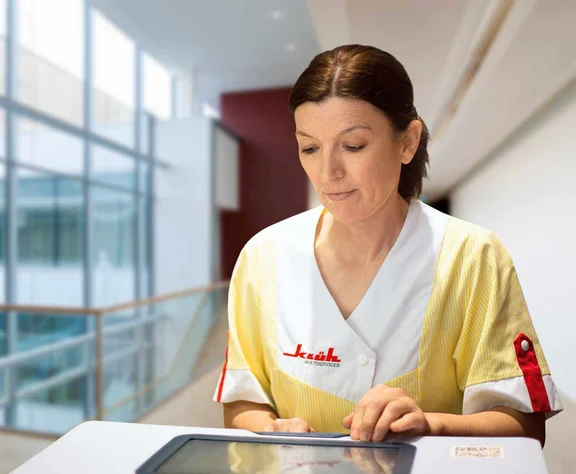 eine Reinigungskraft bedient ein Tablet an ihrem Reinigungswagen