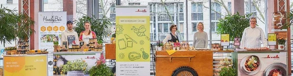Banner mit einem Bild von der Osteraktion von Klüh Catering beim WDR mit mehrern Ständen voller Produkten und leckereien