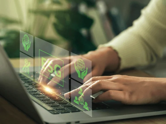 zwei Hände bedienen ein Notebook und über der Tastatur sind Visuell Icons abgebildet in grüner Farbe zum Thema ESG ( Umwelt, Soziales und Unternehmensführung )