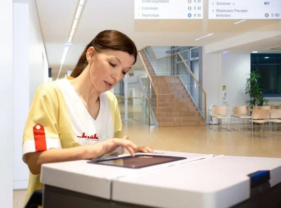 eine Reinigungskraft bei der Arbeit bedient ein Tablet an ihrem Reinigungswagen