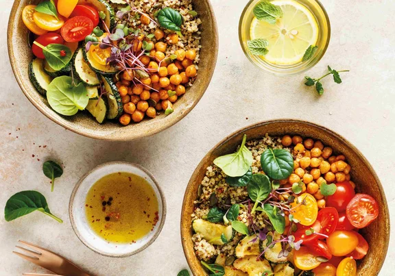 zwei Bowlgerichte bestehend aus Gemüse, Kichererbsen und Quinoa