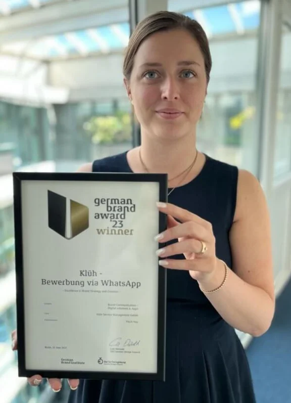 Bild von Frau Viktoria Kaiser, die ein Preis von der german brand award präsentiert mit dem Titel "Klüh - Bewerbung via Whatsapp"