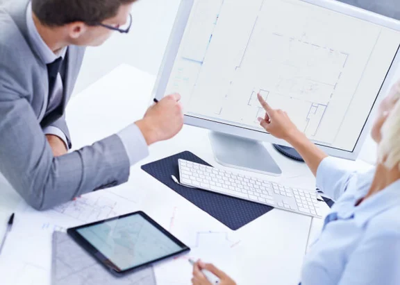 Ein Bild von einem Mann und einer Frau im Büro die gemeinsam Arbeiten und auf den Computer schauen