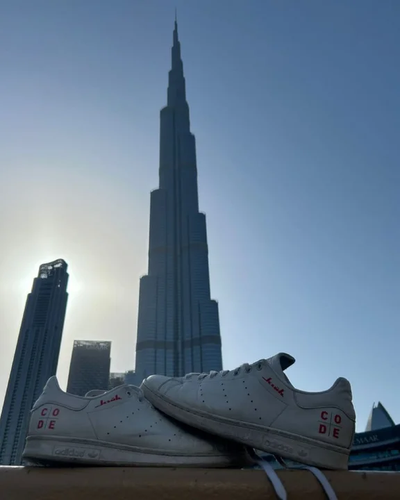 weiße Adidas Schuhe mit Klüh & CODE branding und im Hintergrund der Burj Khalifa