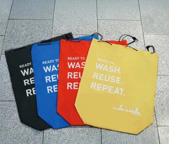 Ein Bild von vier Zipp Beutel von Klüh Cleaning mit dem aufdruck: Ready to WASH. REFUSE. REPEAT. in der farben schwarz, blau, rot und gelb