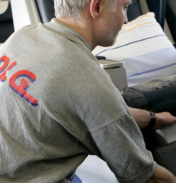 Ein männlicher Arbeiter kontrolliert im Rahmen der sogenannten Cabin Seach die Sitze im Flugzeug.