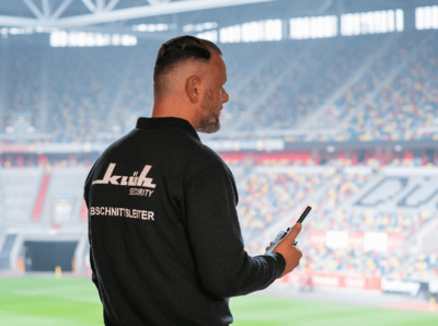 Klüh Security Angesteller in einem Fußball Stadion mit einem Walkie-Talkie in der Hand