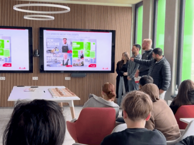 Gruppe Auszubildender die an einem Bildschirm präsentiert