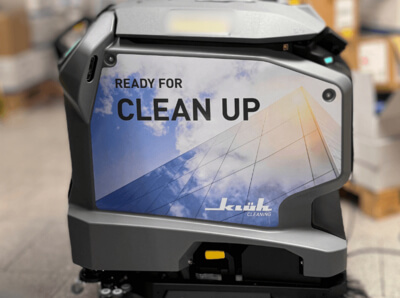 Ein Reinigungsroboter mit einem Sticker an der seite vom Roboter mit der aufschrift: Ready for clean up - Klüh Cleaning