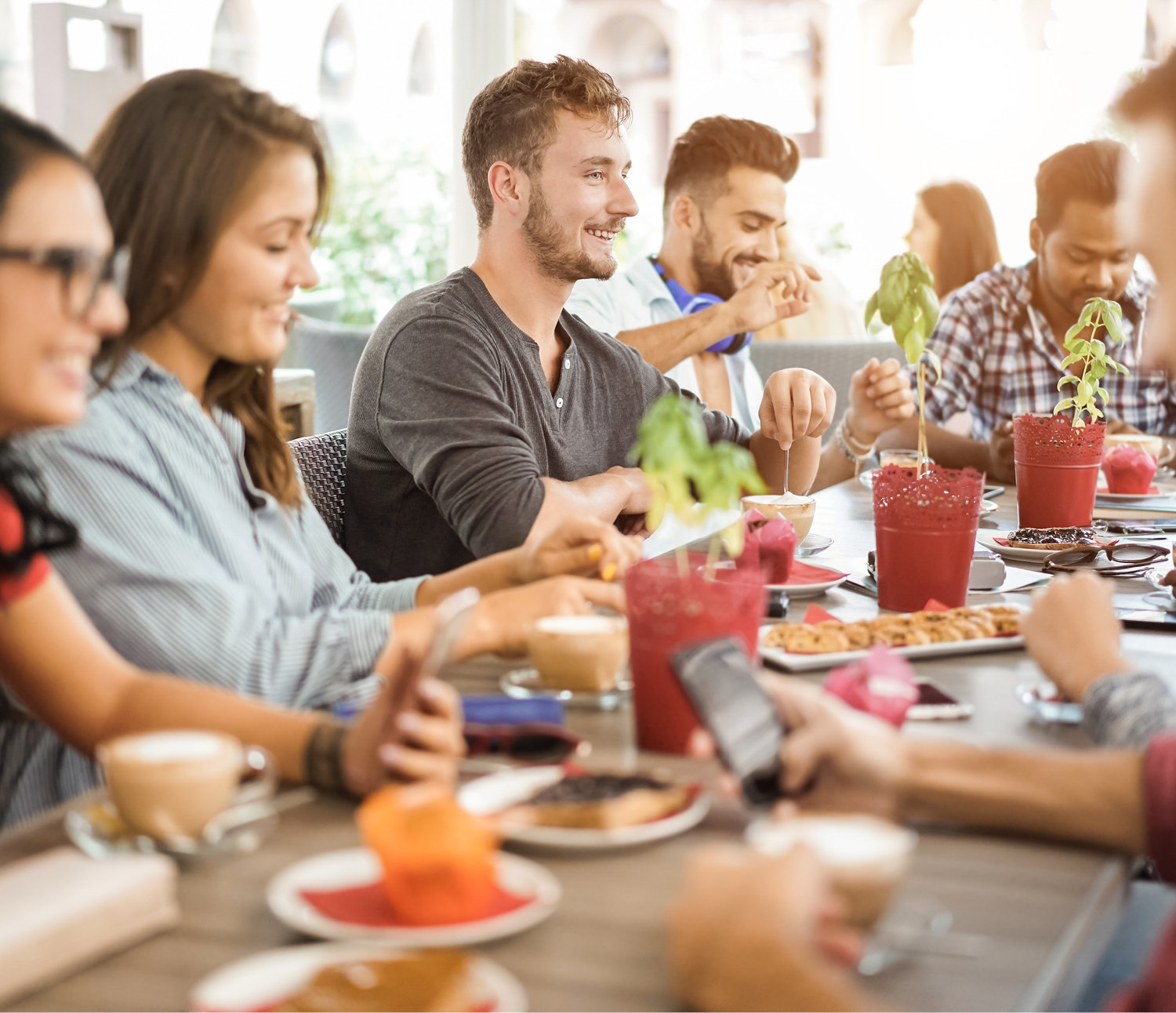 Ein Bild von einer Gruppe von Menschen die am Tisch sitzen und lächeln, auf dem Tisch sind Kaffeetassen und Kuchen 